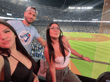 a man wearing a toronto blue jays shirt is standing next to two women