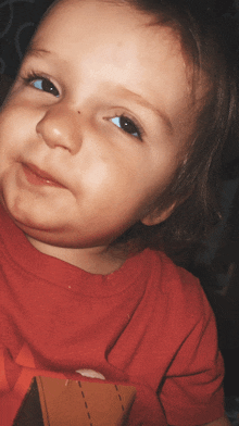 a close up of a child 's face with a red shirt