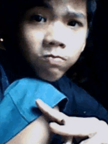 a young boy is making a funny face in a car while holding his arm .