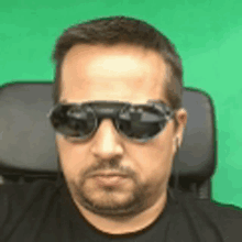 a man wearing sunglasses is sitting in a chair .