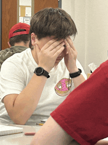 a boy wearing a white shirt with a donut on it covering his eyes