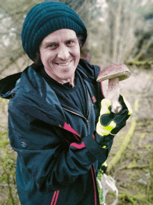 a man wearing a blue hat and a black jacket is holding a mushroom