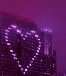 a building with a purple sky in the background has a lot of windows lit up at night