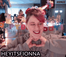 a woman making a heart shape with her hands and the words heyitsfionna written below her