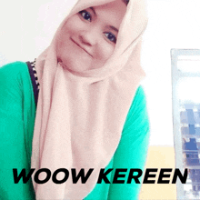 a woman wearing a hijab and a green shirt with the word woow keren on the bottom right