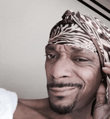 a man wearing a zebra print head scarf smiles for the camera