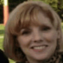 a close up of a woman 's face with a blurred background and she is smiling .