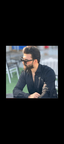 a man with a beard and sunglasses is sitting at a table .