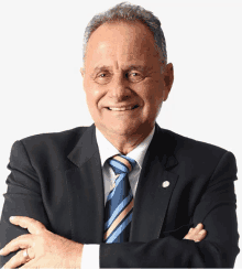 a man in a suit and tie with his arms crossed smiles for the camera