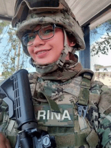 a woman in a military uniform and helmet is holding a gun and smiling .