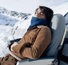 a man in a brown jacket is sleeping on an airplane seat