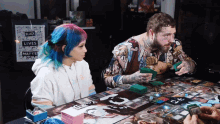 a man and a woman are playing a board game with a sign that says black lives matter in the background