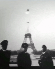 a black and white photo of people standing in front of the eiffel tower in paris