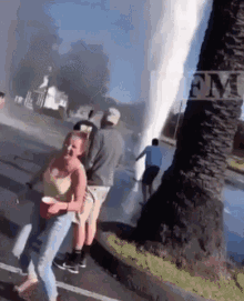 a group of people are standing on the side of the road watching a waterfall coming out of a tree .