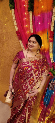 a woman in a maroon colored saree is standing in front of a colorful backdrop