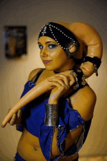 a woman in a blue and yellow costume has a bracelet on her wrist with coins on it