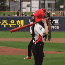 a woman holding a bat on a baseball field in front of a sign that says ' seoul ' on it