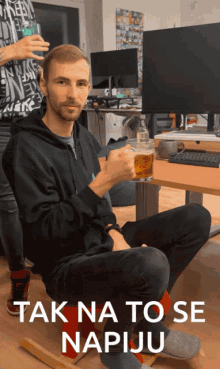 a man sitting on a chair drinking a glass of beer with the words tak na to se napiju behind him