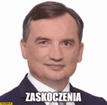 a man in a suit and tie is smiling with the words zaskoczenia written on his face .