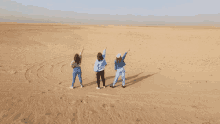 three women are standing in the middle of a desert with their arms in the air