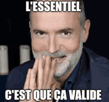 a man with a beard has his hands folded in front of his face and says l' essentiel c'est que ca valide