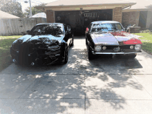 a black car and a red car are parked in front of a house