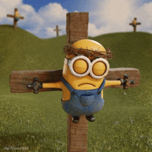 a minion with a crown of thorns on his head is tied to a wooden cross