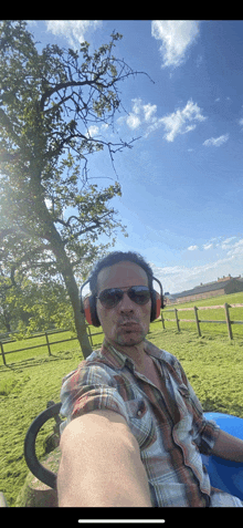 a man wearing headphones is taking a selfie in a field