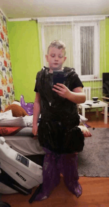 a boy is taking a picture of himself in a room with a vacuum cleaner that says britton on it