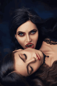 two women dressed as vampires laying next to each other with their mouths open