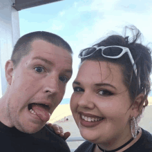 a man and woman are posing for a picture with the woman wearing sunglasses