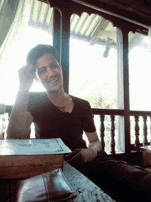 a man with a tattoo on his chest sits at a table with a book on it