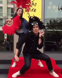 a man and a woman are posing for a picture in front of a building that says southern thai restaurant