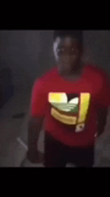 a man in a red adidas shirt is standing in the dark .