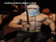 a shirtless man with a bandana on his face is holding a sword in front of a group of people