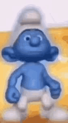 a smurf is standing on a yellow surface and smiling .