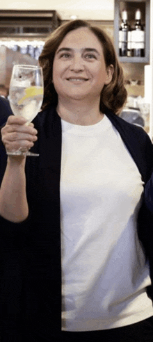 a woman holds up a glass of water with a lemon slice on it