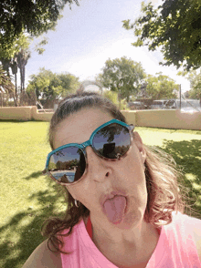 a woman wearing sunglasses making a funny face with her tongue out