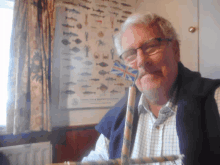 a man wearing glasses holds a british flag in front of a poster of fish