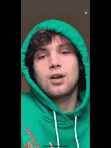 a young man wearing a green hoodie with the letter x on the bottom