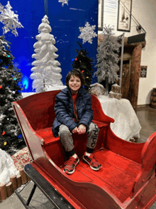 a young boy is sitting in a sleigh wearing adidas shoes