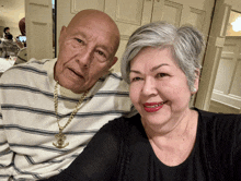 an elderly couple posing for a picture with the man wearing a striped shirt