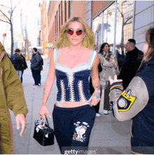 a woman wearing a corset top and sweatpants walking down a street