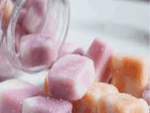 a jar filled with pink and orange ice cubes is sitting on a table .