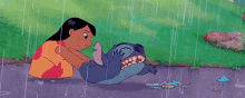 a cartoon character , stitch , is laying on the ground in the rain with a woman .