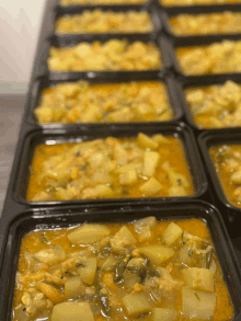 a row of containers filled with a yellow colored stew