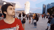 a man wearing a red shirt with the word coca cola on it stands in front of a crowd of people