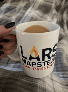 a person holding a coffee mug that says lars mapstead for president