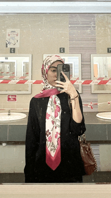 a woman taking a picture of herself in a bathroom with a sign that says tamil on the wall