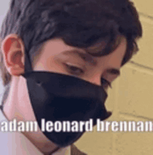 a close up of a man wearing a face mask with the name adam leonard brennan on the bottom